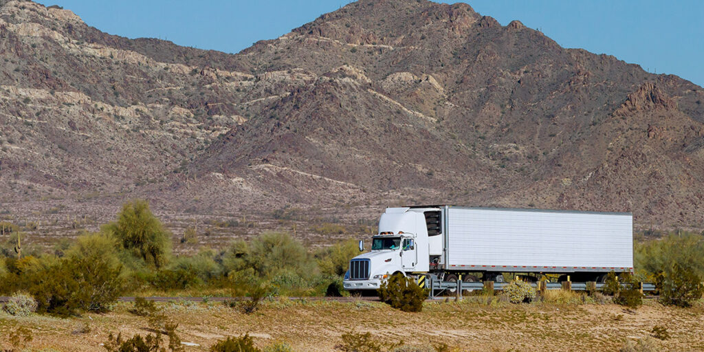 white-reefer-semi-traveling-through-mountains Reefer truck crossing through a mountain highway