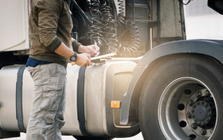Driver writing shipment temperature on a clipboard outside truck