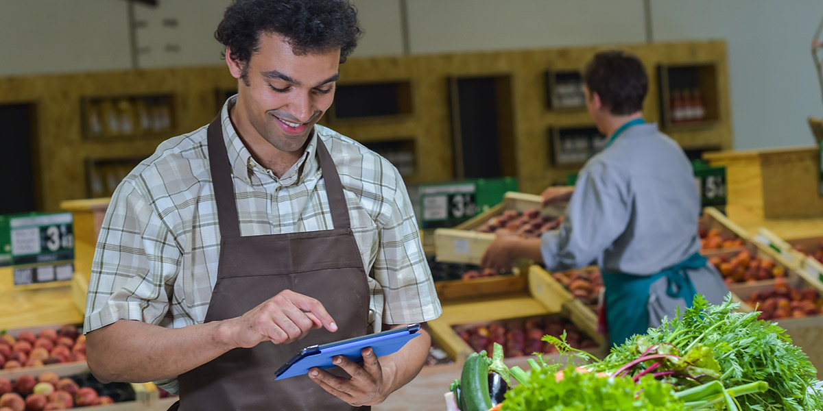 Produce employee with tablet smiling