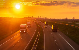 Hot and hazy yellow sun sky above a busy highway with reefer trucks.